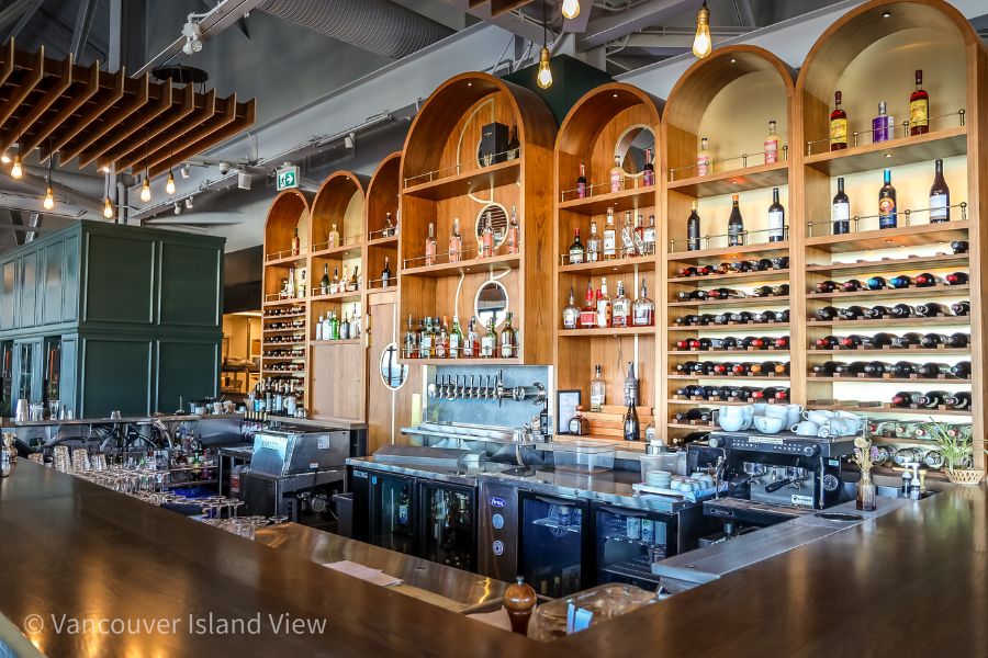 A beautiful wooden bar filled with backlit alcohol bottles at Nanoose Bay Cafe - a waterfront gem in Nanoose Bay bc. Vancouver Islan d View